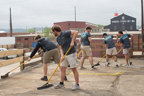male students sweeping concrete