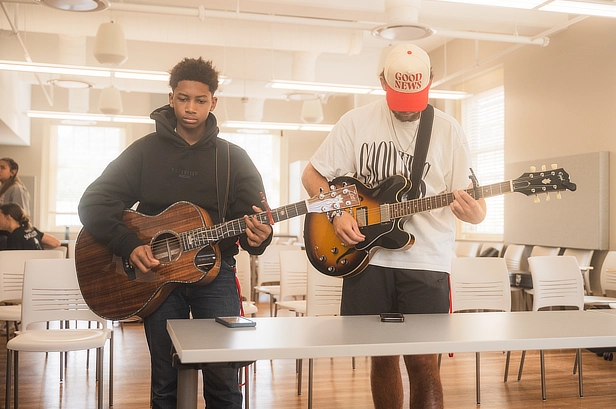 two male students playing guitar
